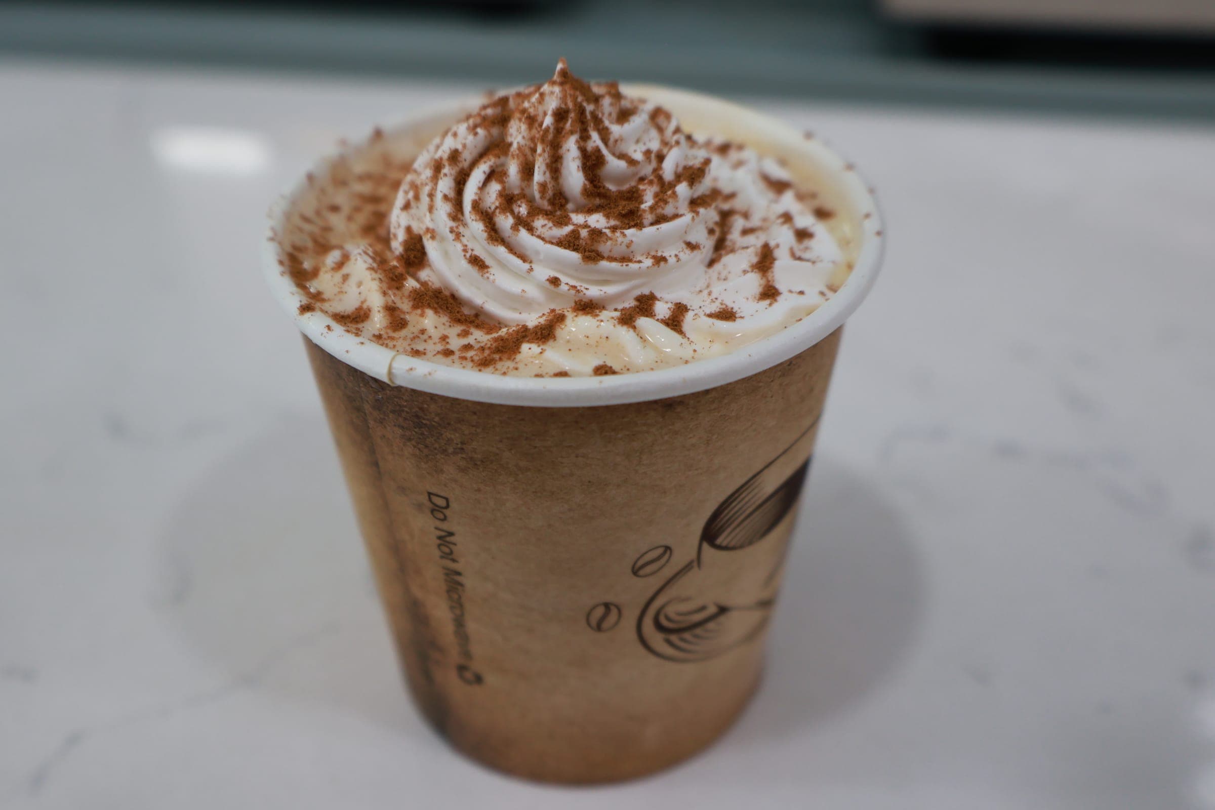 A cup topped with whipped cream and a dusting of cocoa