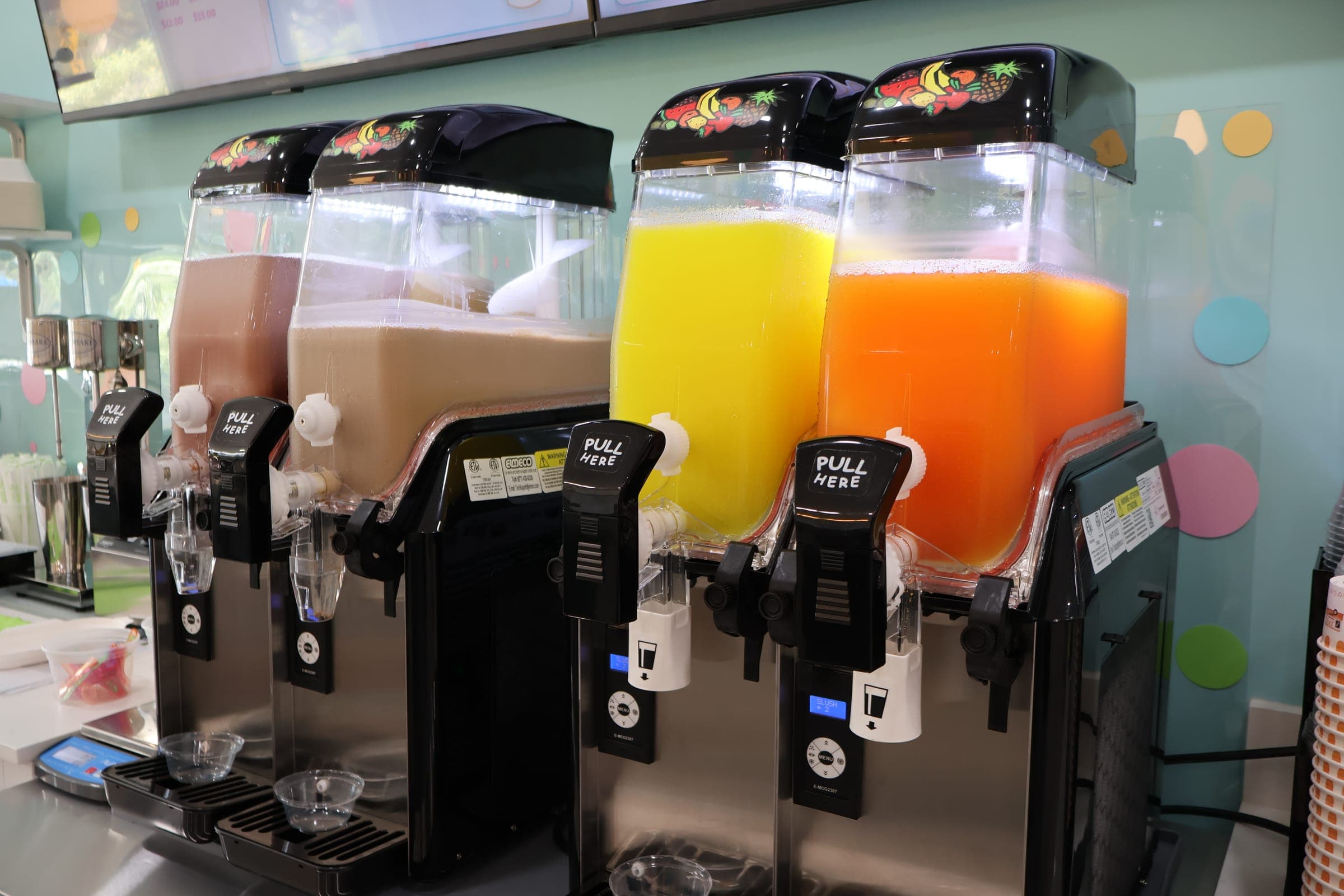 Granita machines swirling chocolate, lemon and orange frozen drinks