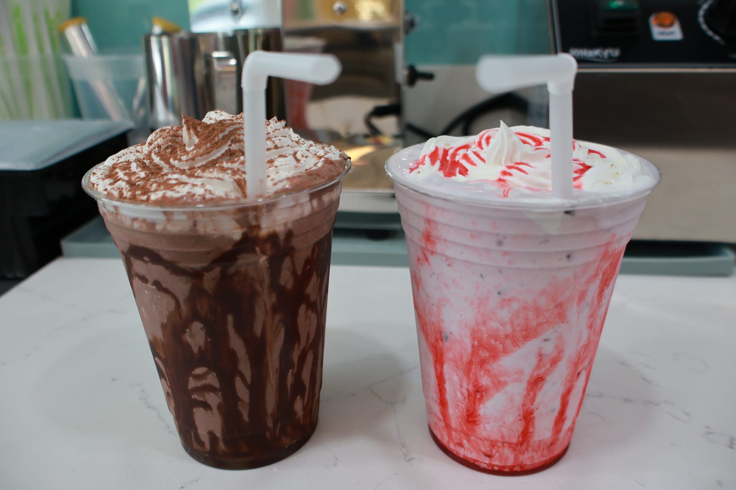 A chocolate milkshake and a strawberry milkshake with whipped cream